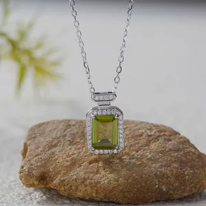 Detailed macro view of square green gemstone pendant necklace displayed on a natural stone base