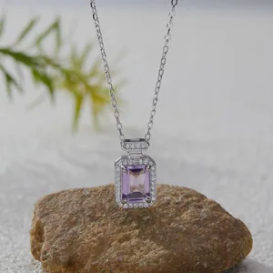 Detail of a S925 silver necklace featuring a rectangular purple gemstone pendant on a rock.