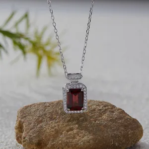 Close-up of a square red garnet pendant featuring a brilliant halo setting on natural stone.