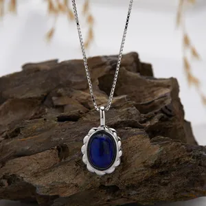 Silver box chain necklace with oval lapis lazuli pendant on natural rock