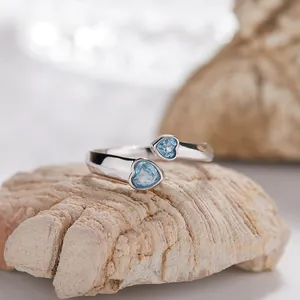 Vista macro dettagliata di un anello aperto in argento S925 con due topazi blu a cuore