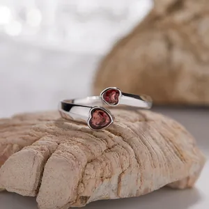 Dettaglio macro di un anello in argento S925 con due cuori di granato rosso.