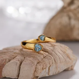 Primo piano dell'anello aperto dorato con due pietre di topazio blu a forma di cuore