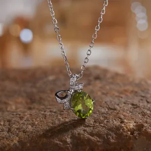 Detailopname van een S925 zilveren ketting met natuurlijke peridoot en strik hanger