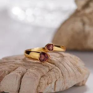 Vista dettagliata di un elegante anello in argento dorato con due granati rossi a cuore