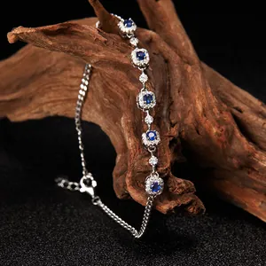 Primer plano de una pulsera de plata S925 con piedras azules y diseño halo en madera natural