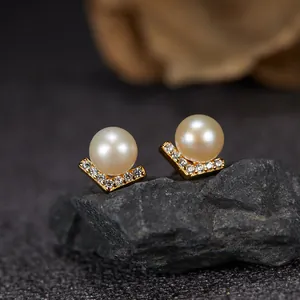 Detailed macro view of V-shaped S925 silver stud earrings with freshwater pearls.