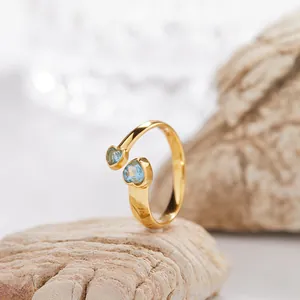 Dettaglio di un anello aperto in argento dorato con due pietre di topazio blu a cuore.