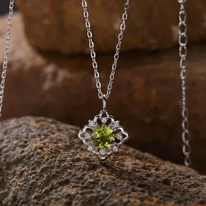Detailaufnahme einer Silberhalskette mit Peridot-Anhänger auf natürlichem Steinhintergrund