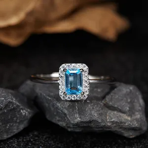 Detailed macro shot of an emerald-cut blue topaz silver ring on dark stones.