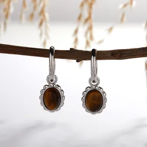 Detailed view of silver hoop earrings featuring oval natural tiger's eye stone pendants