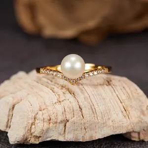 Macro detail of a V-shaped golden sterling silver ring with a lustrous freshwater pearl.