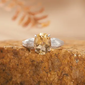 Primo piano di anello in argento S925 con citrina gialla ovale e motivo a foglie