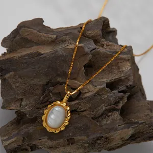 Close-up detail of a gold necklace with an oval white shell pendant on natural rock