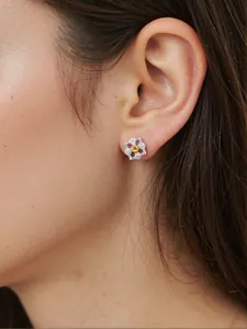 Nahaufnahme eines silbernen Blumensteckers mit gelbem Stein am Ohr eines Modells