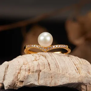 Macro detail of elegant V-shaped gold ring featuring a natural white freshwater pearl