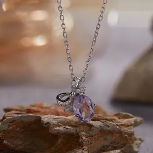 Detailopname van een paarse amethist strikhanger aan een zilveren ketting.