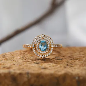 Nahaufnahme eines eleganten S925 Ringes mit blauem Topas und Diamant-Halo-Verzierung