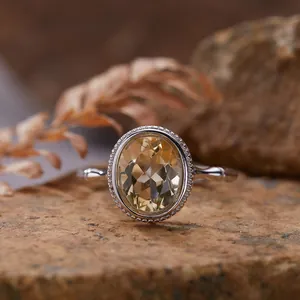 Close-up of S925 sterling silver ring with oval yellow gemstone on natural stone background.