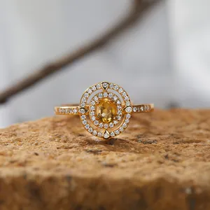 Detaillierte Nahaufnahme eines Goldrings mit gelbem Edelstein und Halo-Pavé-Diamantfassung