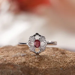 Nahaufnahme eines S925 Silberrings mit hohlem Blumendesign und ovalem rotem Edelstein