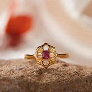 Nahaufnahme eines goldenen Rings mit rotem Edelstein und floralem Hohlmuster-Design