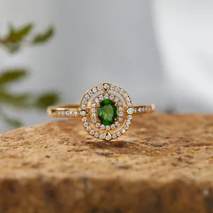 Nahaufnahme eines Goldrings mit grünem Diopsid-Edelstein und Doppel-Halo auf Stein