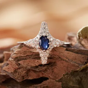 Primo piano di un anello a stella a quattro punte in argento con zaffiro blu ovale.
