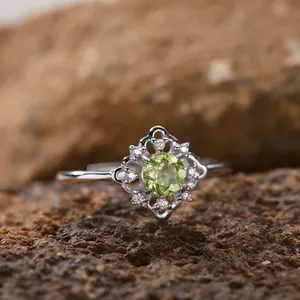 Makro-Detail eines Sterlingsilberrings mit natürlichem grünem Peridot auf strukturiertem Fels.