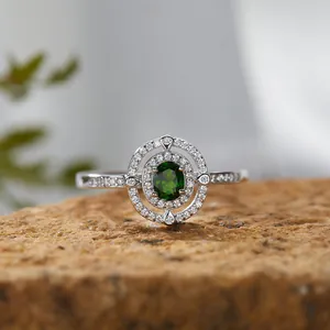 Nahaufnahme eines S925-Silberrings mit grünem Diopsid-Edelstein und funkelndem Halo.