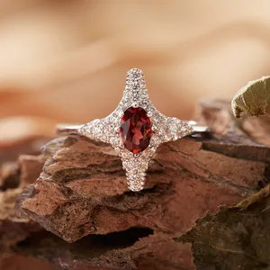 Dettaglio dell'anello a stella a quattro punte in argento S925 con gemma rossa ovale.