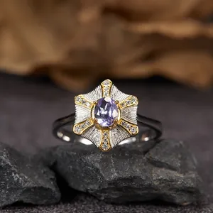 Macro di un elegante anello in argento con gemma ovale viola e castone a stella dorata
