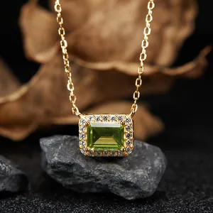 Detailed macro view of an emerald-cut peridot pendant with a sparkling gemstone halo