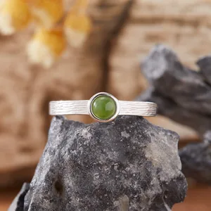 Primo piano di un anello di giada nefrite verde naturale con fascia in argento S925 testurizzata
