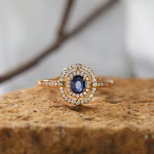 Nahaufnahme eines Vintage-Rings mit blauem Saphir-Halo auf strukturiertem Stein