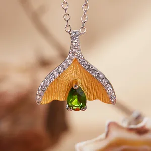 Gedetailleerd zicht op een vissenstaart hanger ketting met groene edelsteen pavé