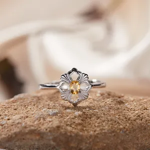 Makroansicht eines Vintage-Silberblumenrings mit gelbem Edelstein auf einem rustikalen Stein
