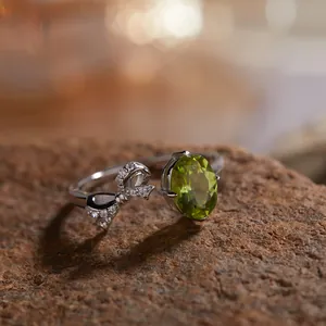Macro detail van een S925 zilveren open ring met ovale peridoot en kristallen strik