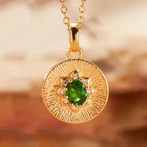 Close-up of gold pendant necklace with green gemstone and radiant sunburst texture