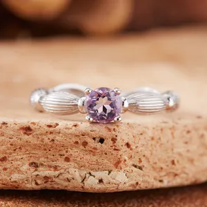 Macro detail view of a natural round faceted purple amethyst gemstone set in a textured silver ring