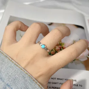 Vista dettagliata di un anello in argento S925 con pietra turchese sul dito di una donna