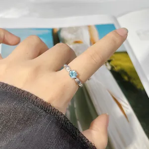 Close-up detail of an S925 silver ring with a round blue topaz gemstone worn on a hand