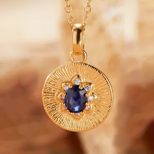 Close-up of a gold-plated silver pendant with a central oval blue tanzanite gemstone
