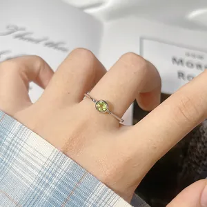Dettaglio macro di un delicato anello in argento S925 con una pietra preziosa verde.