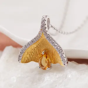 Close-up van een S925 zilveren vissenstaart hanger met gele edelsteen en zirkonia.