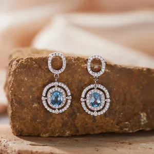 Nahaufnahme der S925-Silberohrringe mit ovalem blauem Topas und glitzernden Zirkonen.