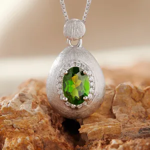 Macro view of a brushed S925 silver teardrop pendant with an oval green gemstone