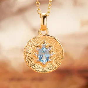 Close-up of golden sunburst pendant with light blue oval gemstone and zircon detail
