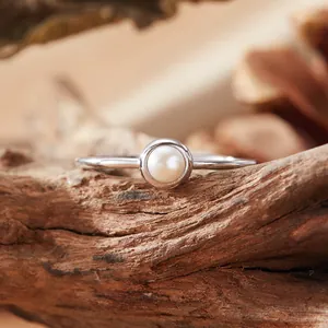 Macro view of minimalist S925 sterling silver ring with elegant white pearl on wood