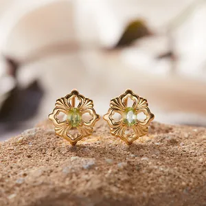 Detailaufnahme der Vintage-Ohrstecker aus Gold mit Peridot-Edelstein auf Naturstein